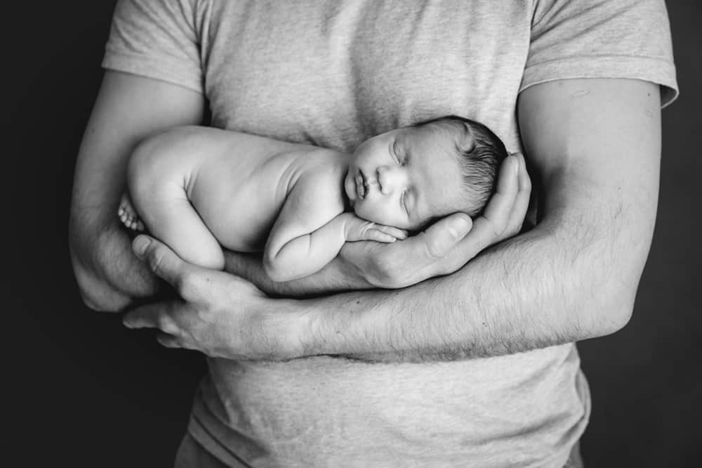 black and white image of a father holding sleeping baby