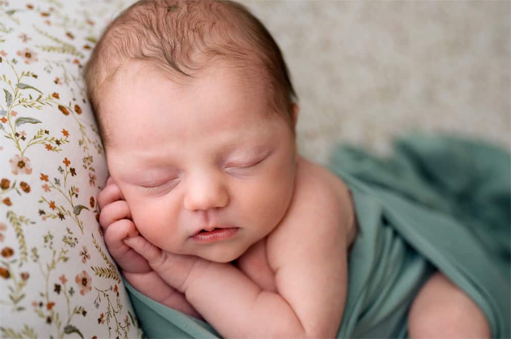 sleeping newborn baby lying on flowery fabric