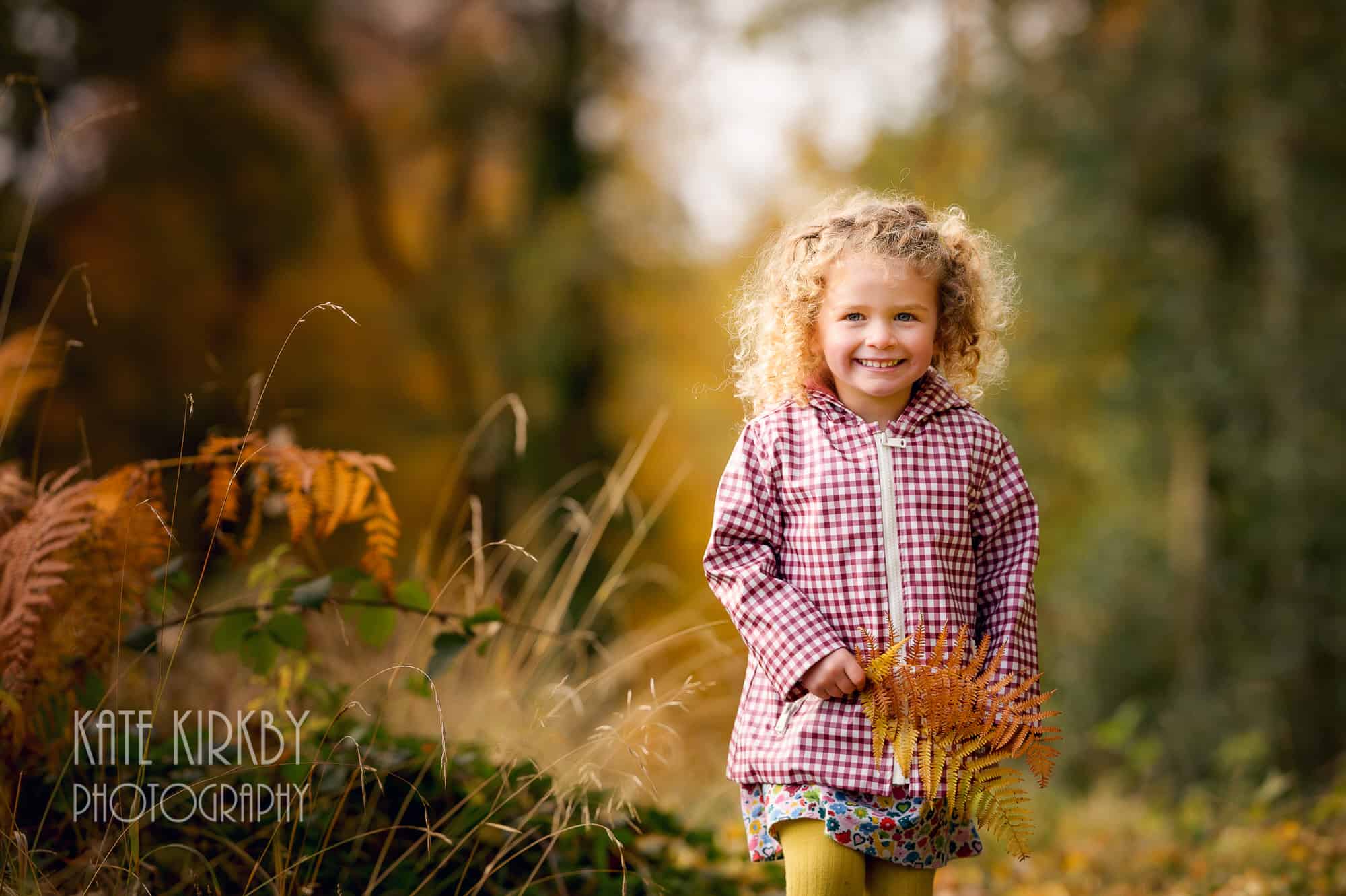 young girl with big blonde girls holding autumn fern leaves
