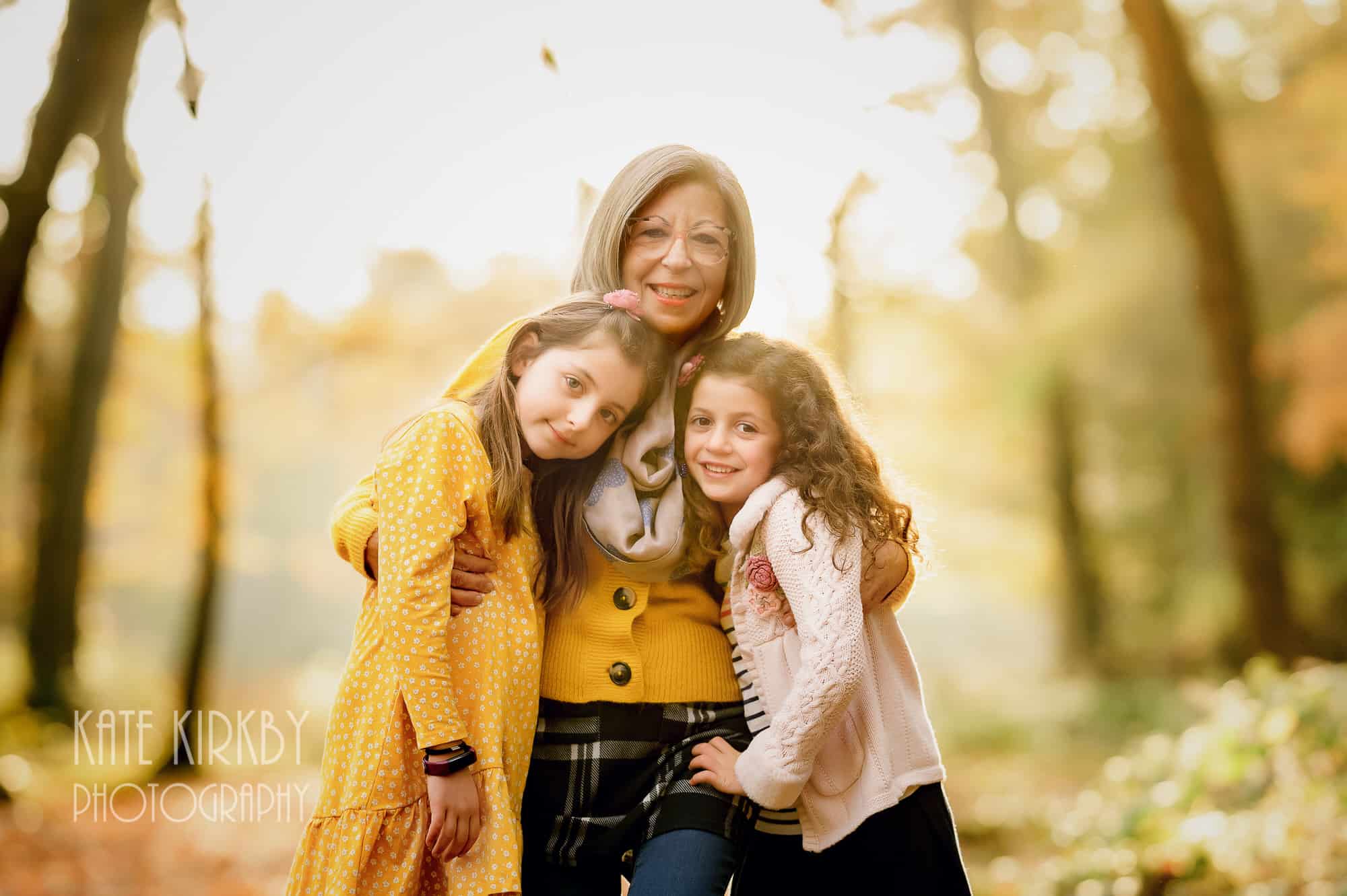 two girls and grandmother in autumn woodland