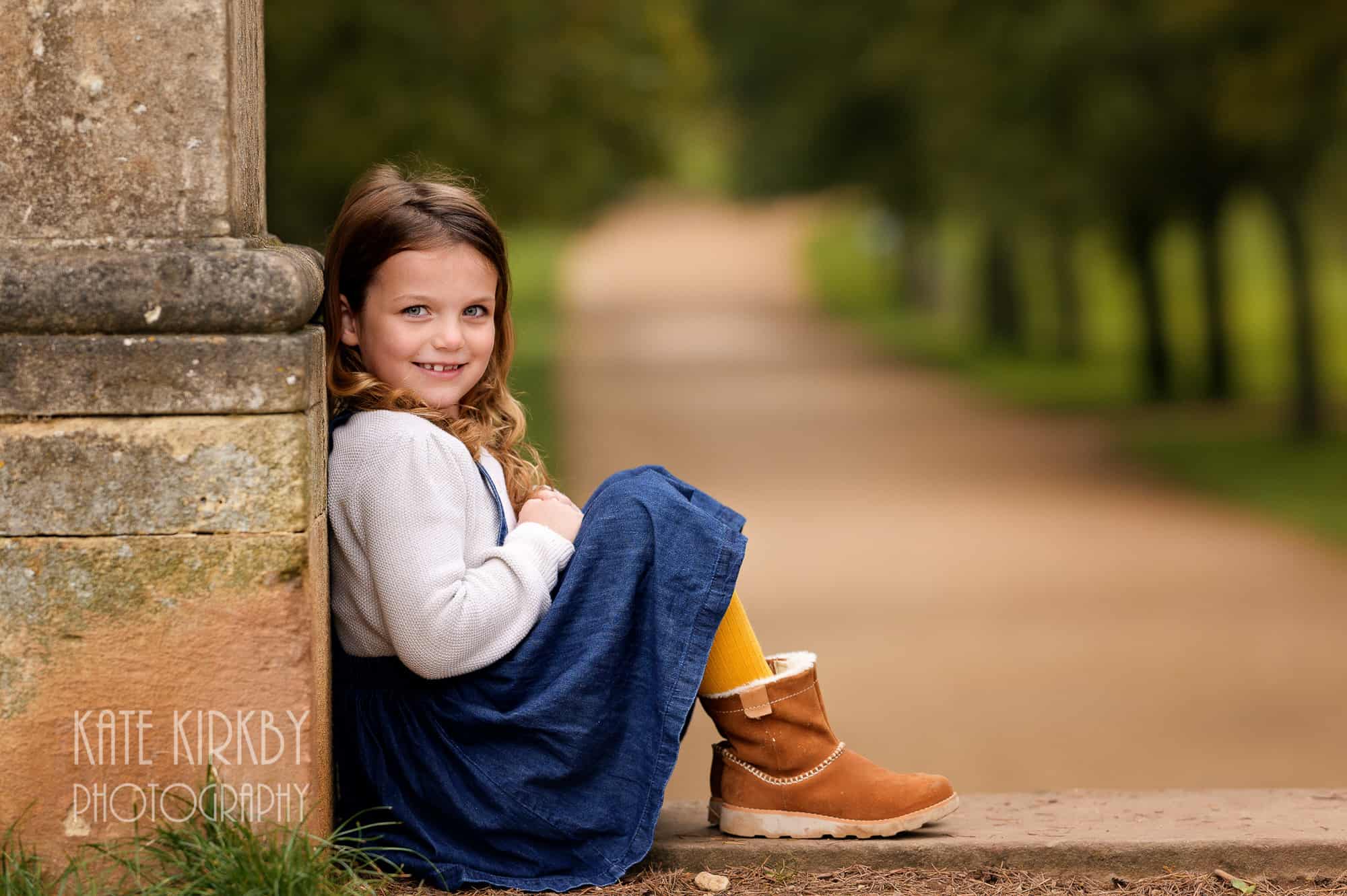 girl siting on top step with tree lined path leading away in background