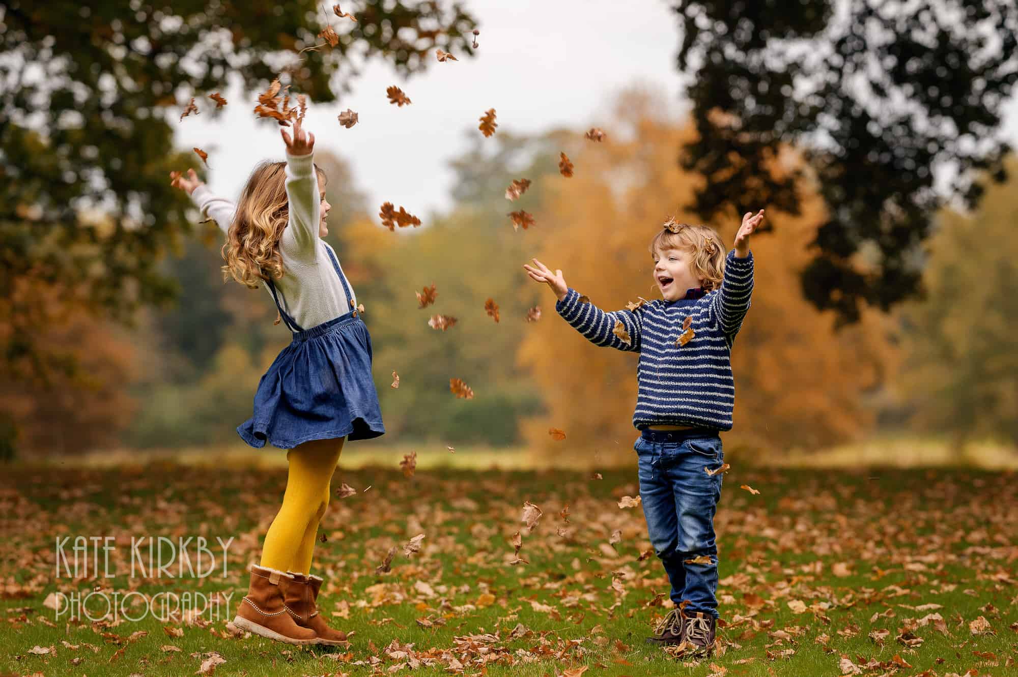 brother and sister throwing autumn leaves