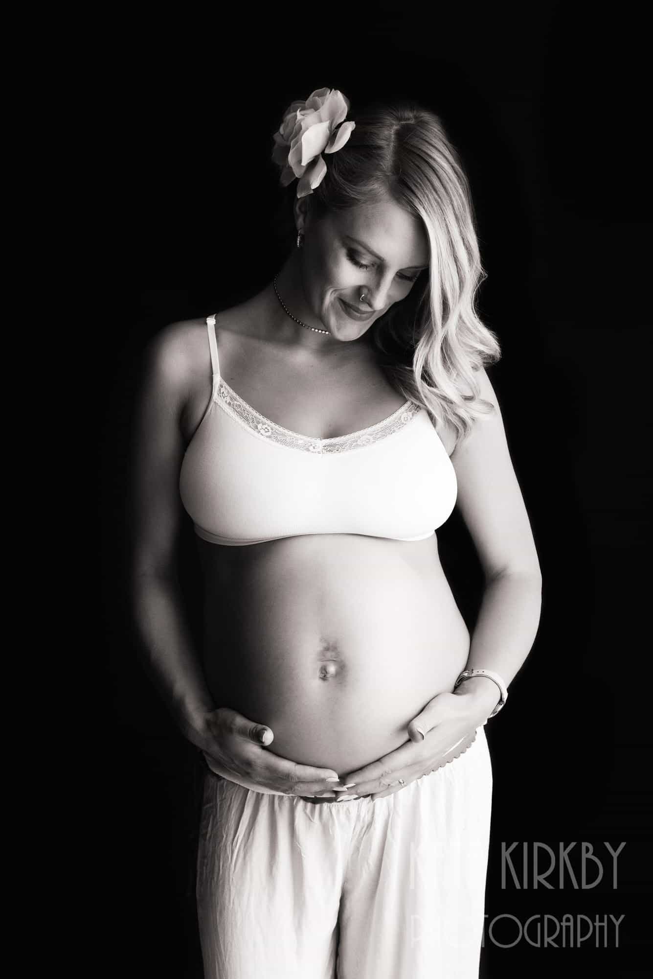 pregnant woman on black background cradling her belly