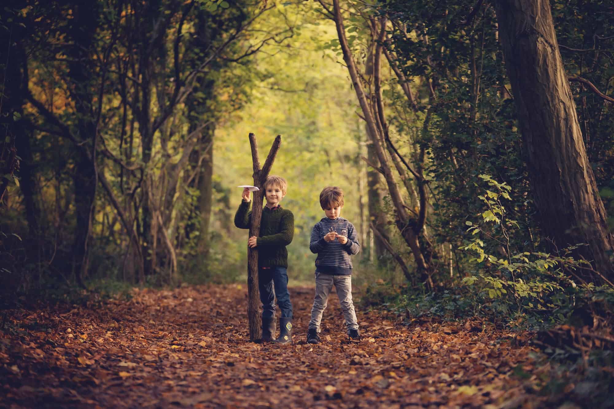 brothers in autumn woods with big stick