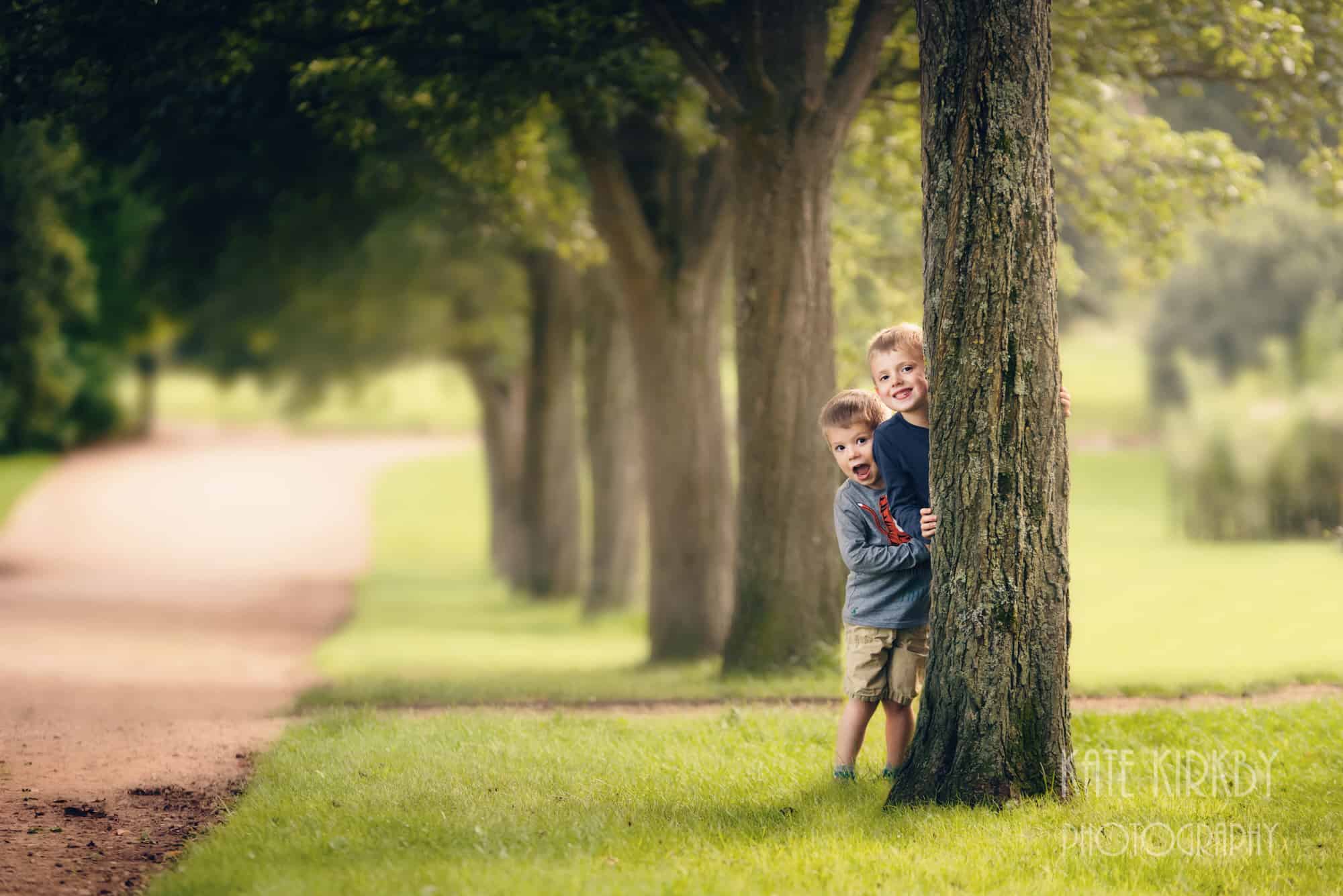 brothers playing peek a boo behind a tree