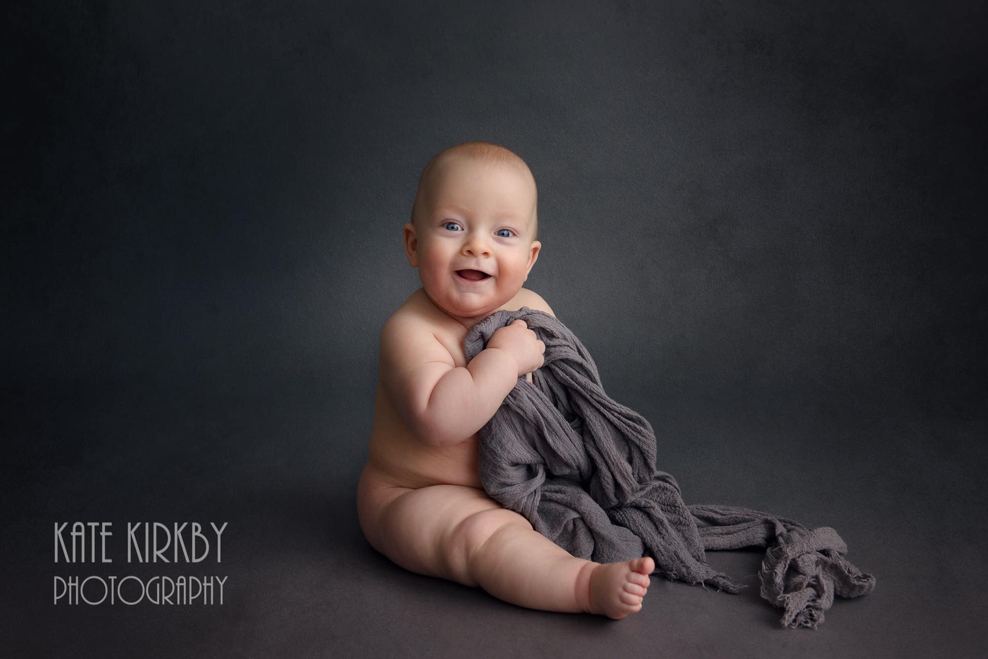 baby on grey background holding grey scarf