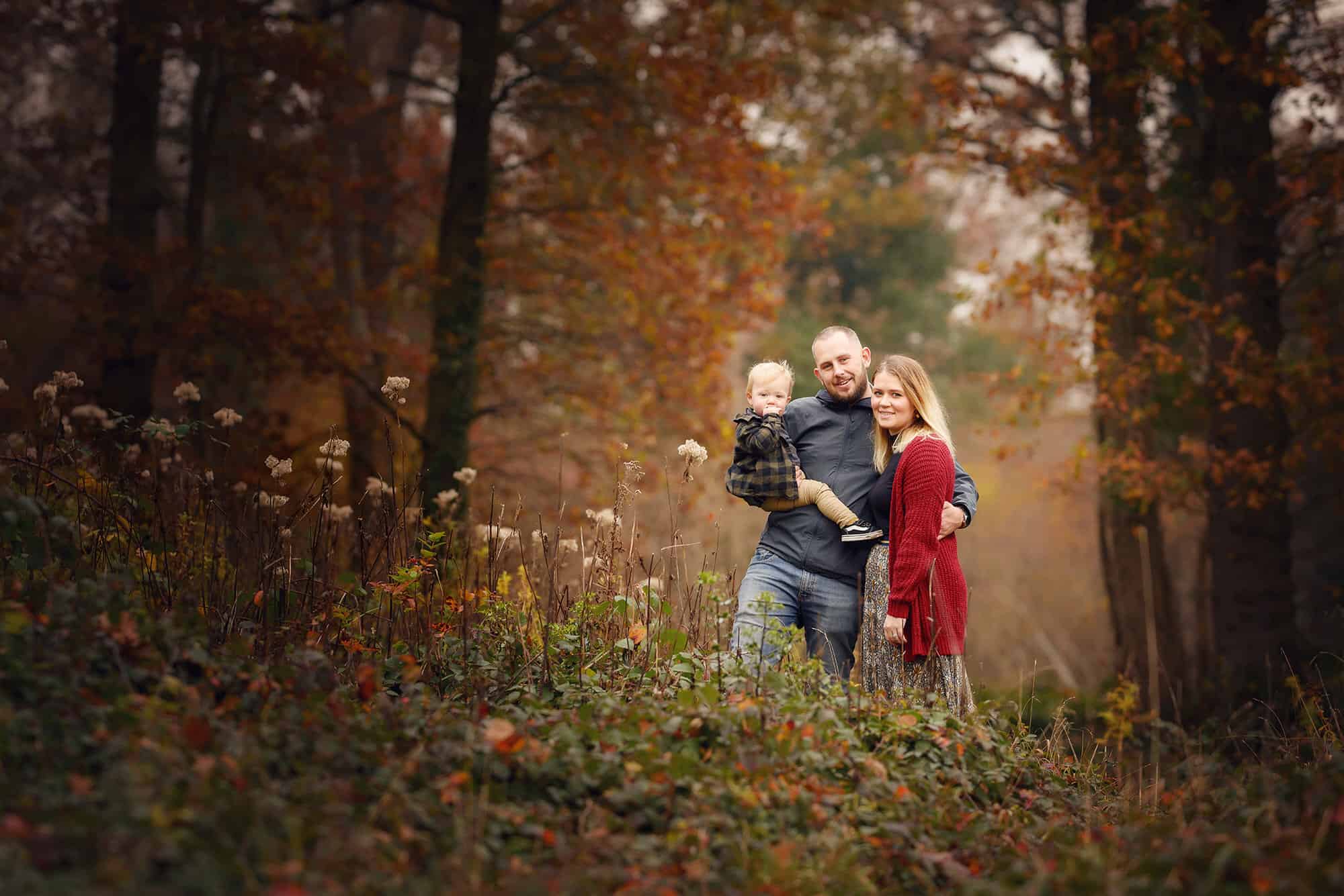 mum, dad and young boy standing in autumn woodland