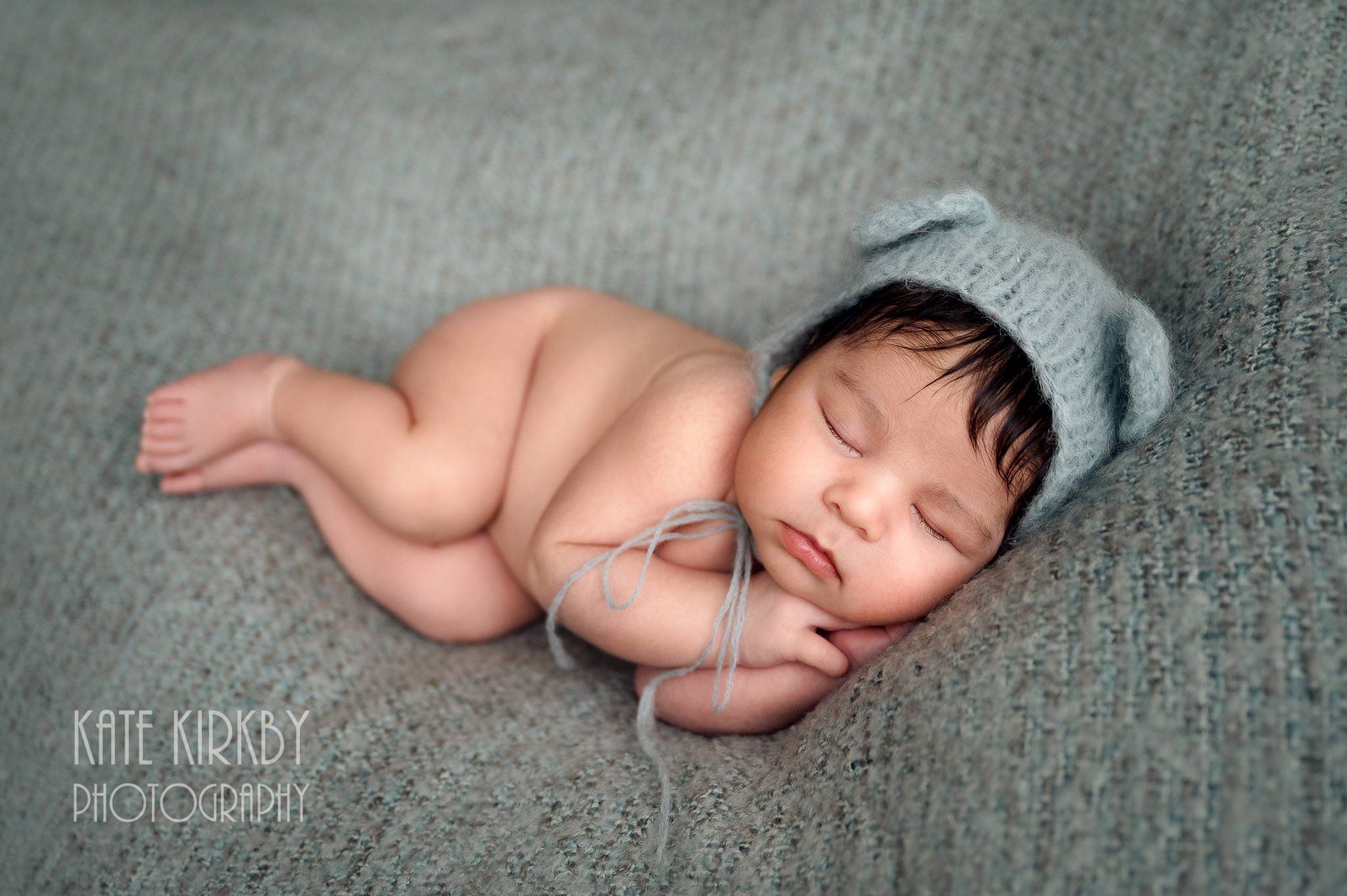 sleeping newborn on blue with teddy hat