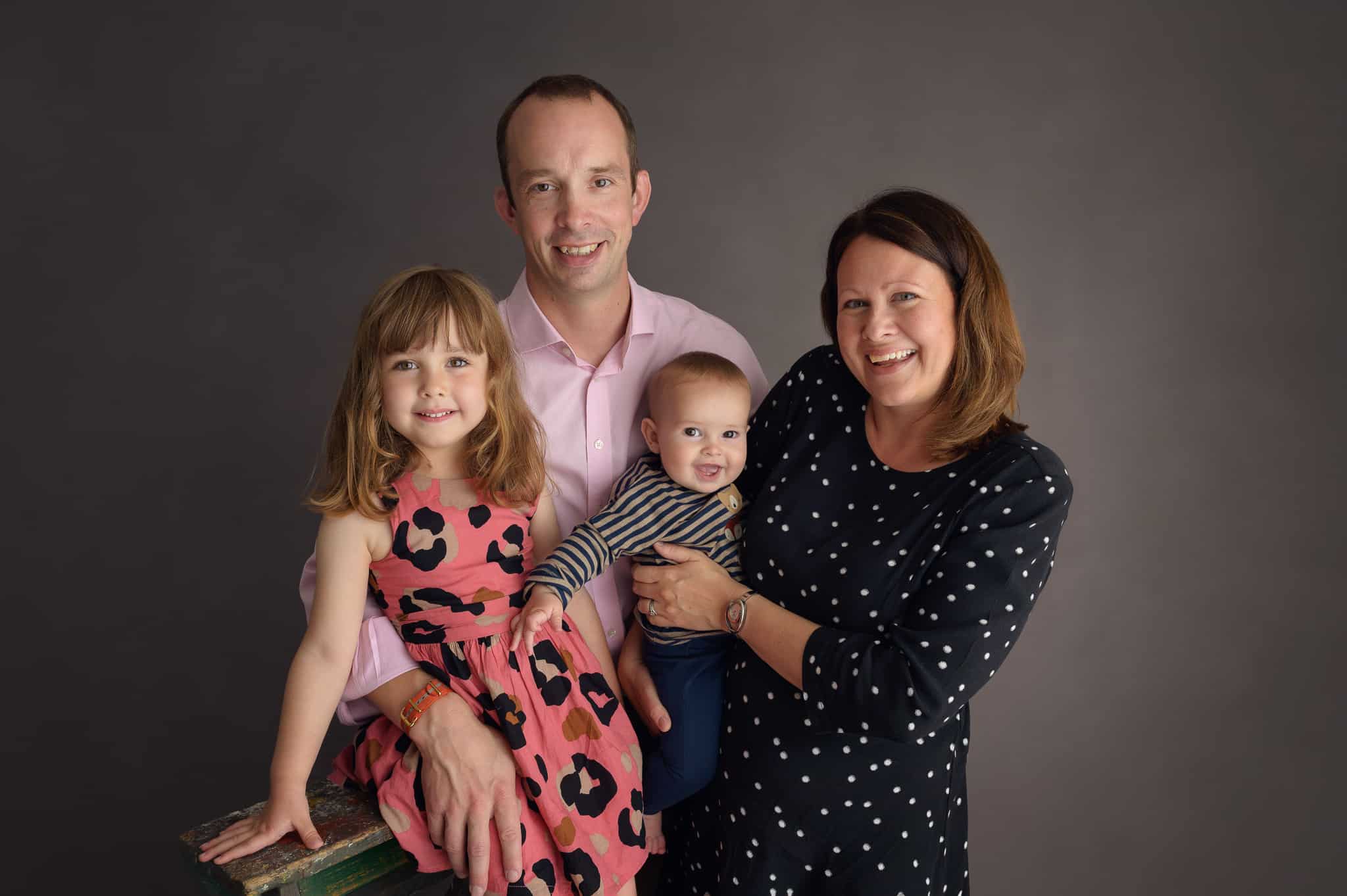 smiling family with two children on grey background