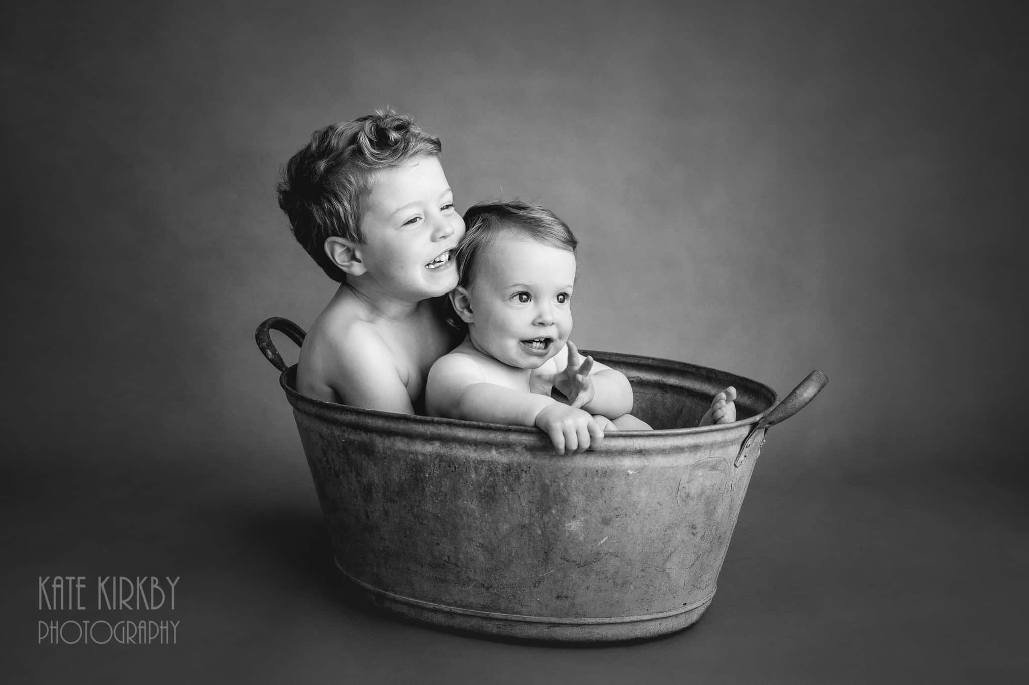 bother and sister sitting in old tin bath