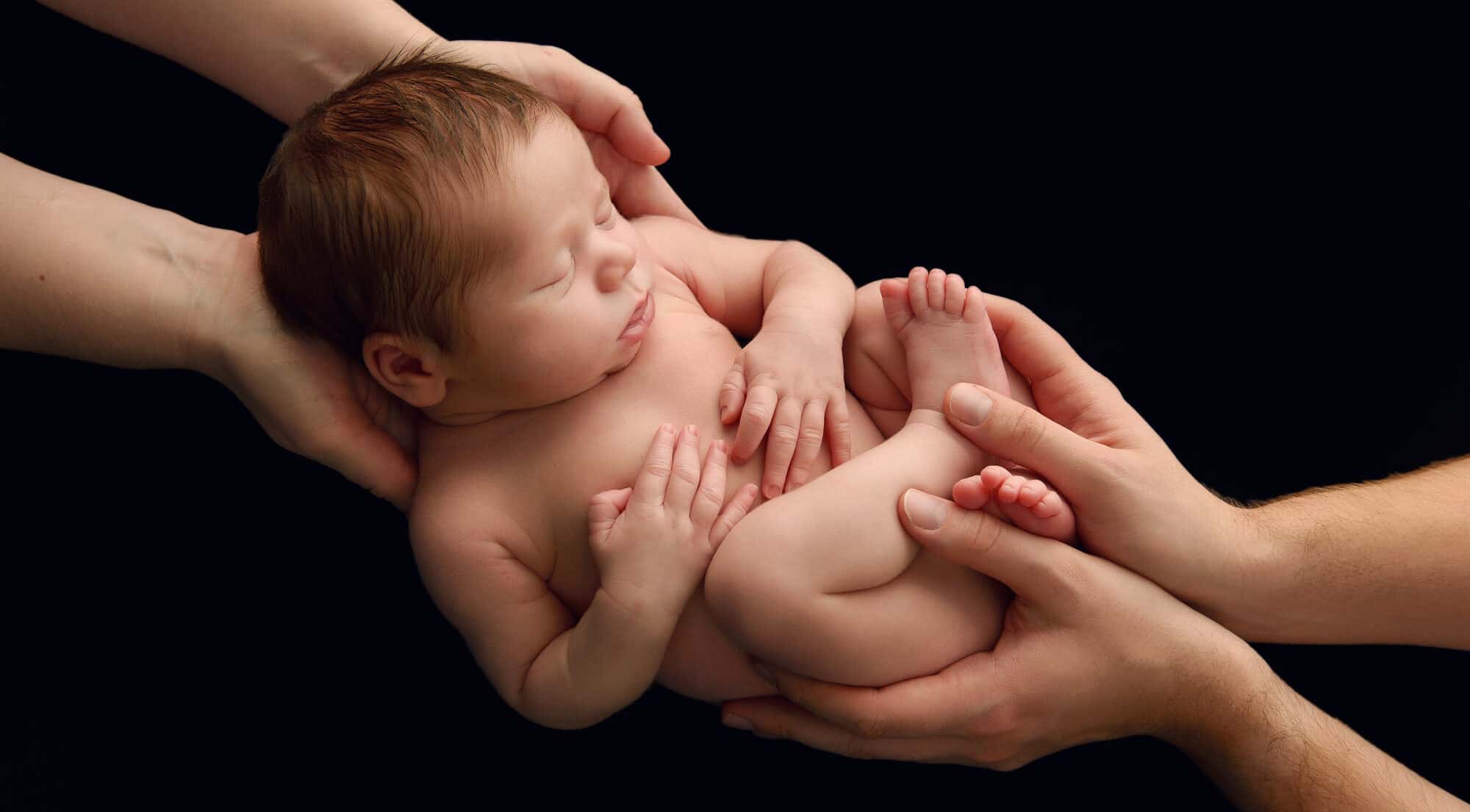 photography of newborn baby held in parents hands in Bristol