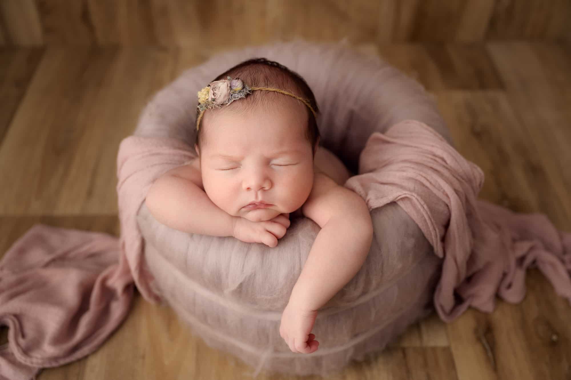 newborn baby in pink with flower tieback