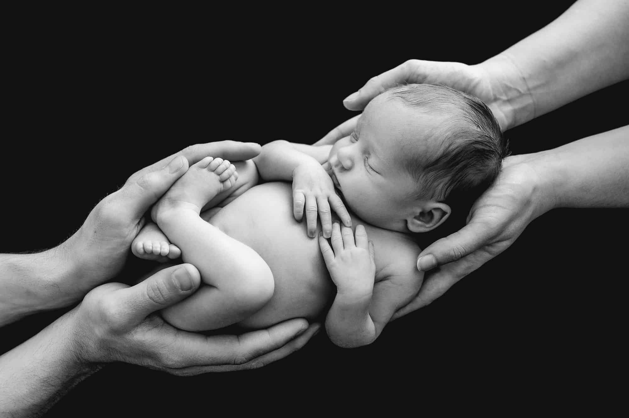 slepping newborn photo in parents hands