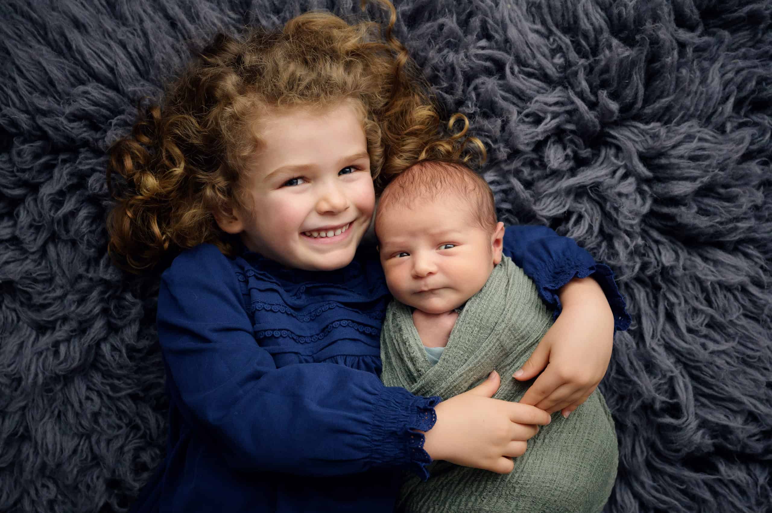 photograph of a Big sister cuddling newborn baby brother in a studio in Bristol