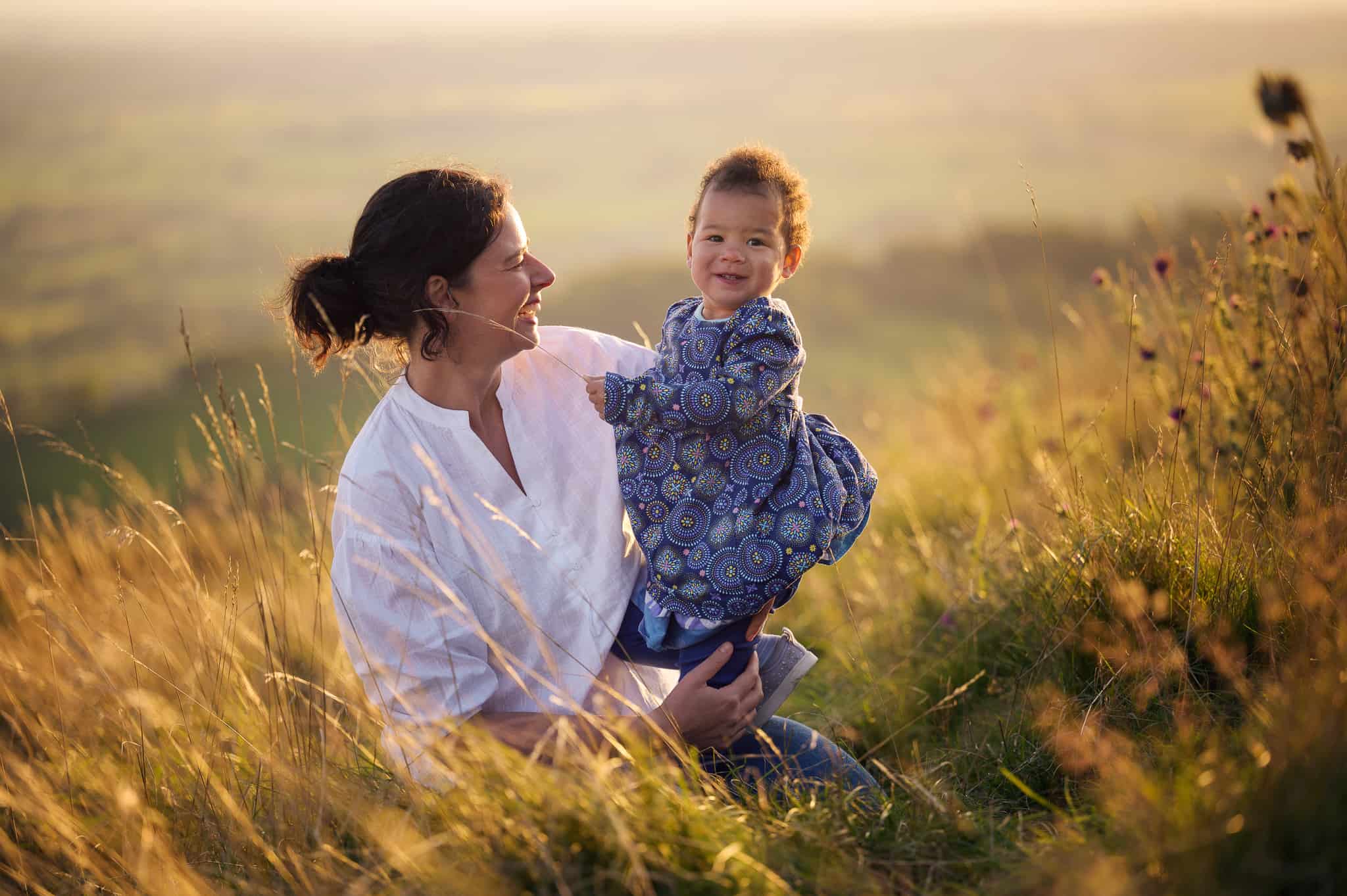 Mother and daughter photograph sitting in a field at sunset