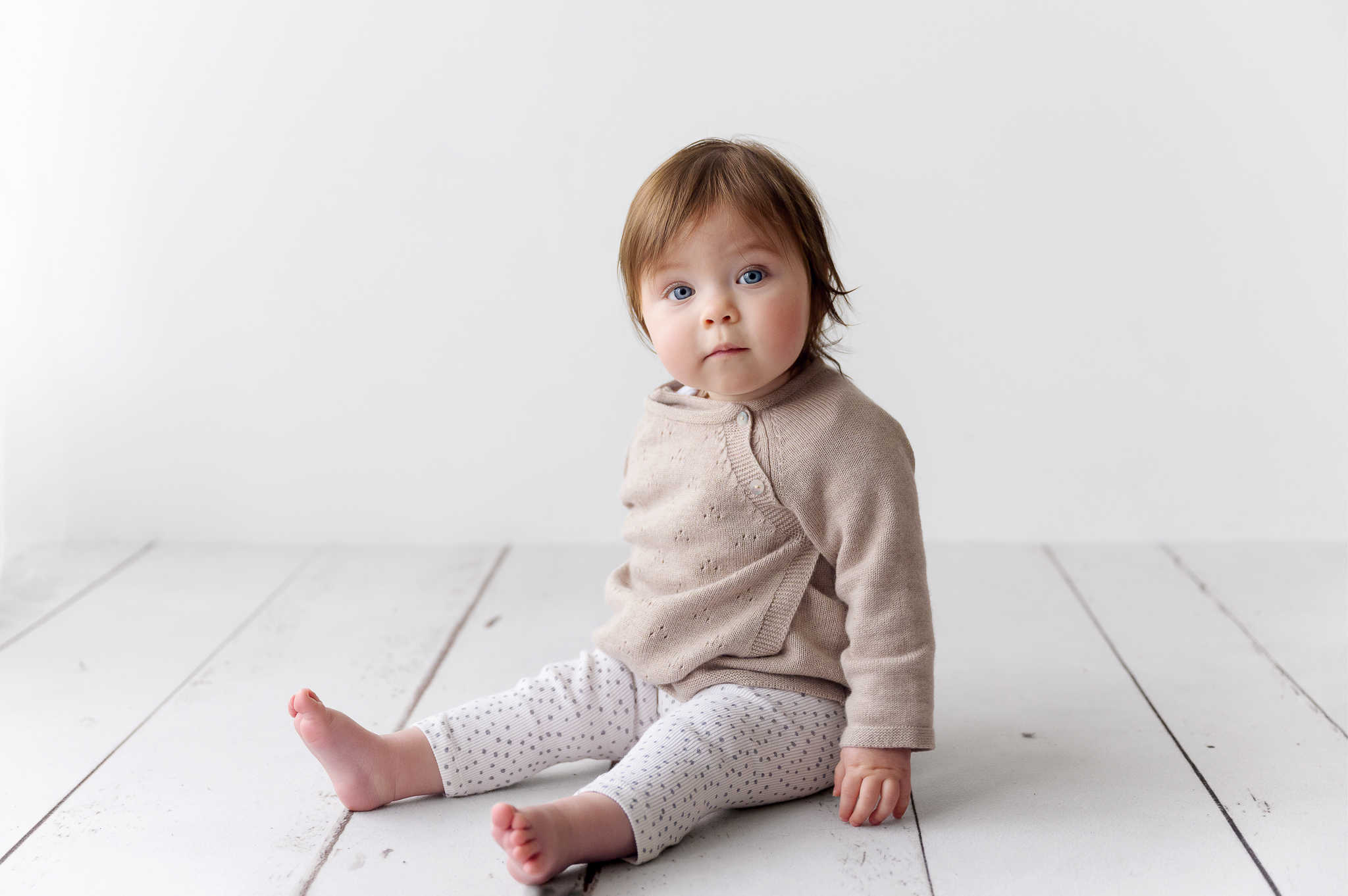little girl sitting on white floorboards