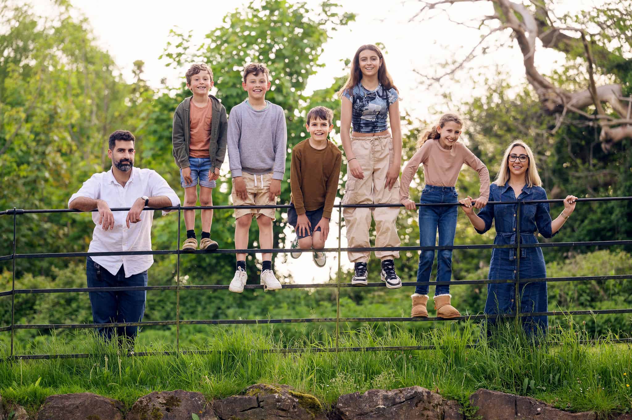 photograph of a family with 5 children standing on a fence in Ashton Court