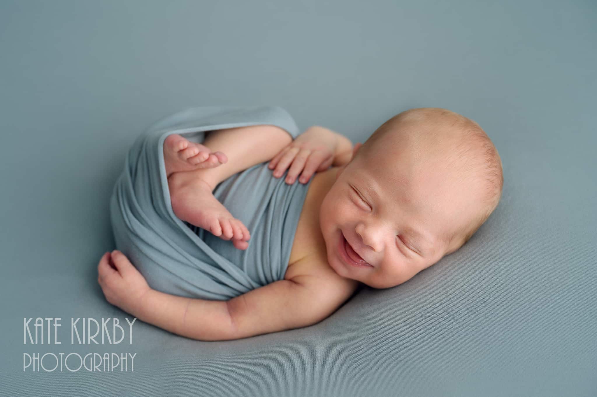 photo of newborn baby boy smiling on blue background