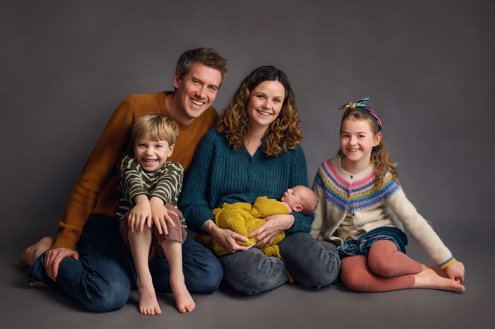 studio family portrait with newborn baby on grey background